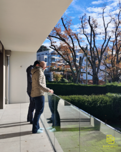 Chefs de projet Titouan and Thibault admire the view from a balcony at the new homes overlooking a luscious green garden.