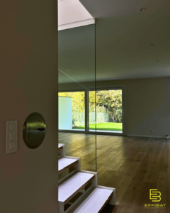 the view of the interior of Villa A as seen from the staircase with light cascading down sun-lit steps and light filling the room from the large bay windows.