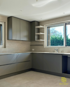 The luminous interior of a kitchen with gray cabinets and cream-tiled walls.