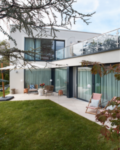 Exterior view of the home with large glass windows reflecting light in the backyard