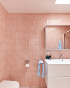 A salmon-colored tile bathroom lit by a sky light