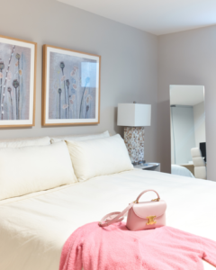 A bedroom with pink throw and purse