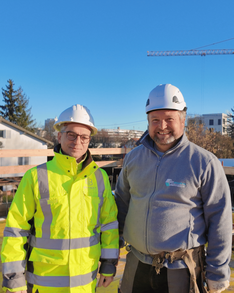 Chef de projet Sébastien côte à côte avec un maçon sur chantier