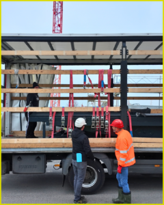 two men observe the car elevator on the back of a flatbed truck.